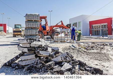 Zrenjanin Vojvodina Serbia - September 14 2015: Workers are helping forklift to place on right place plate compactor machine.