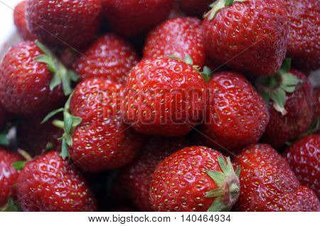 Ripe red strawberries with green leaves close up