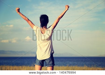 cheering young woman open arms to beautiful landscape