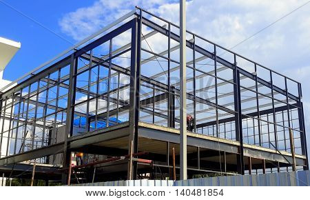 steel frame, two-story building being built at a construction site, with blue sky and clouds, Songkhla, Thailand