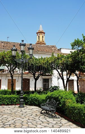 Streetlight and bench in the Plaza las Flores with the church tower to the rear Estepona Malaga Province Andalucia Spain Western Europe.