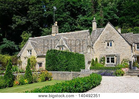 Pretty Cotswold cottages and gardens during the Summertime Bibury Cotswolds Gloucestershire England UK Western Europe.