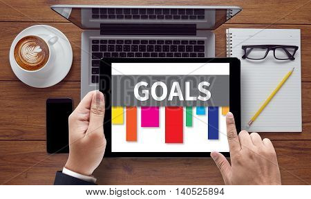 GOALS on the tablet pc screen held by businessman hands - online top view
