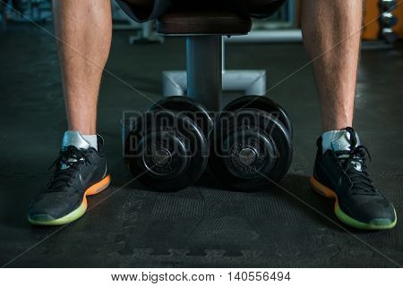 Feet and dumbbells in modern gym during fitness training