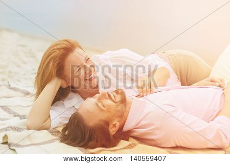 Toned picture of attractive mature couple relaxing on beach near by sea. Beautiful people kissing and enjoying their free on beach.