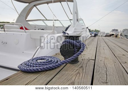 Mooring rope with a knotted end tied around a cleat on a wooden pier
