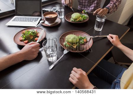 Closeup picture of vegan dishes represented onblack wooden table in vegan restaurant or cafe while business people communicating.