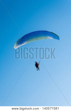 Paragliding in the sky. Man flying a paraglider on the sun.