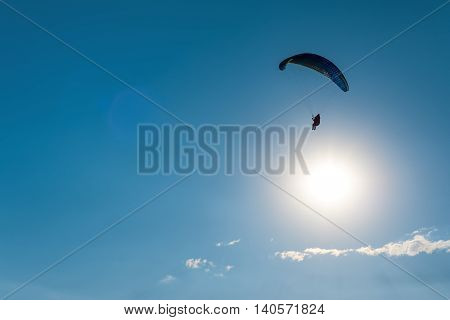 Paragliding in the sky. Man flying a paraglider on the sun.