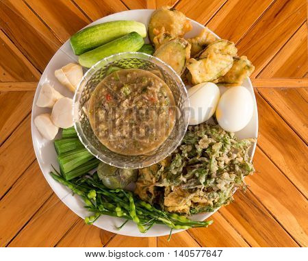 Fermented fish spicy dip with boiled eggs and vegetables in white dish .