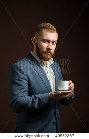 Portrait of red haired elegant man in suit with cup of coffee looking at camera.Isolated.