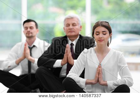 Business people relaxing in meditation pose in office