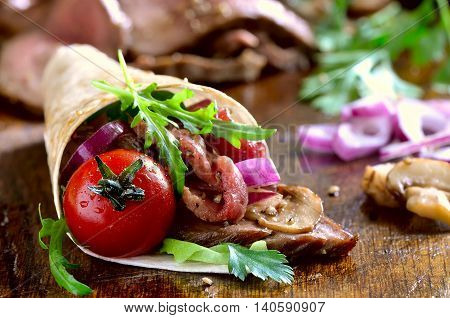 Spicy wpapped fajito with grilled beef and various greens such as lettuce cilantro arugula and spanish onion