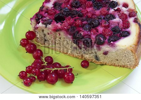 Summer berry pie and fresh redcurrants on a green plate.