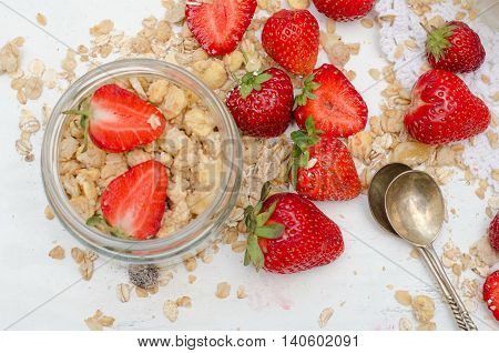Ripe and tasty strawberries with scattered muesli on white background