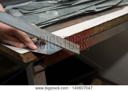 Artisan polishes sharp metal edge - closeup trade