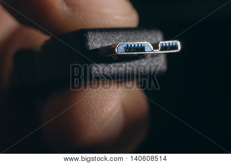 Hand holding black micro USB 3.0 cable. Man's hand holds a USB Connector.
Closeup man hand holding USB cable.Selective focus and shallow Depth of field.