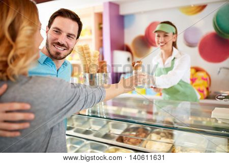Smiling man buying ice cream his girl in pastry store 