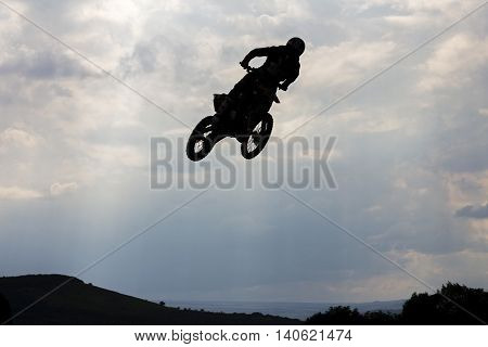Jumping motorcircle rider silhouette on sky background.
