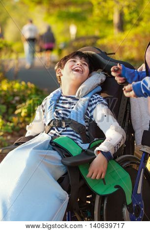 Smiling nine year old boy in wheelchair enjoying time at park outdoors
