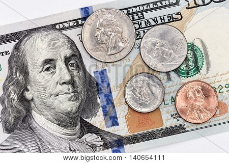A hundred american banknote with coins of all denomination