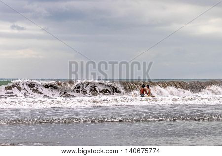 Bali,Indonesia-May 28,2010:Tourist enjoying swimming with big wave at Kuta beach,Bali,Indonesia.Kuta Beach,Bali has one of the best beach scenes in Asean.
