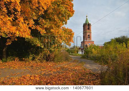 autumn landscape with yellow leaves on trees and a view of the bell tower of the Church