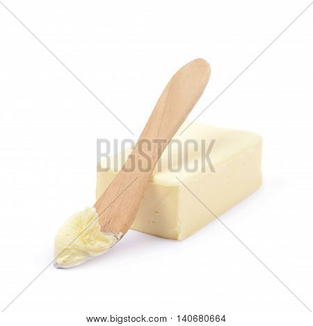 Wooden knife over a briquette piece of a butter, composition isolated over the white background