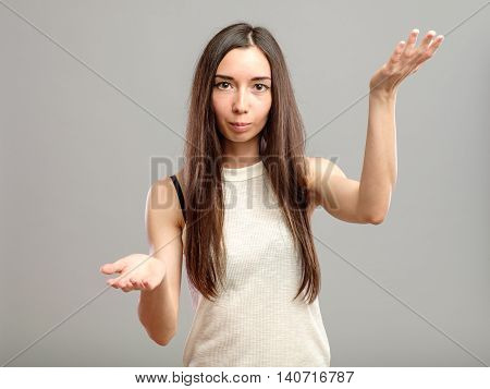 Attractive woman holding her hands out saying that she does not know isolated over gray background