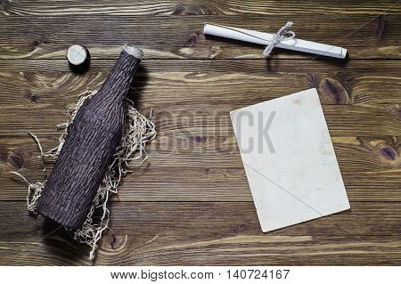 Antique rolled message and old bottle. Old paper on brown aged wood. Written message on paper for put in the glass bottle