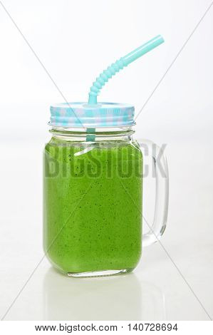 Jar tumbler mug with green smoothie drink over white