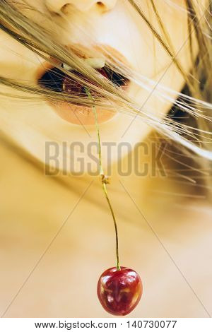 Red cherries pair hang from young woman mouth with rosy sensual lips