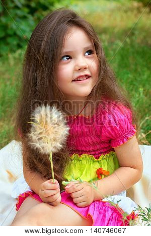 Pretty little girl sitting on a beige cover with fluffy flower