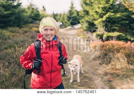Woman hiking with akita inu dog on forest trail. Recreation and healthy lifestyle outdoors autumn woods in mountains inspirational nature. Fitness and trekking and activity concept.