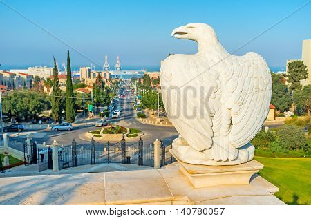 The sculpture of white stone eagle in Bahai Garden and the Ben Gurion Boulevard on the background Haifa Israel.