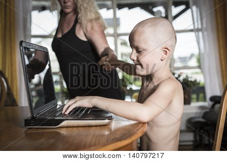 A boy with internet dependence playing with keyboard being dragged by mother from her computer