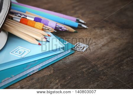 Pencil case with various stationery on old  wooden table