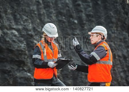 Two speacialists examining coal at an open pit