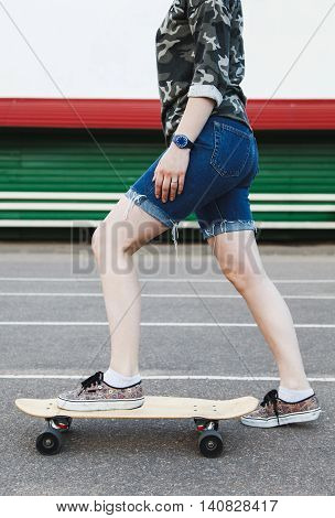 Sexy hipster girl rides a longboard at the stadium