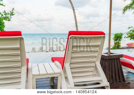 Beautiful beach chairs with umbrella around outdoor swimming pool neary sand and sea