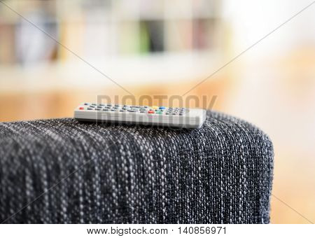 remote control lying on an armrest of a sofa.