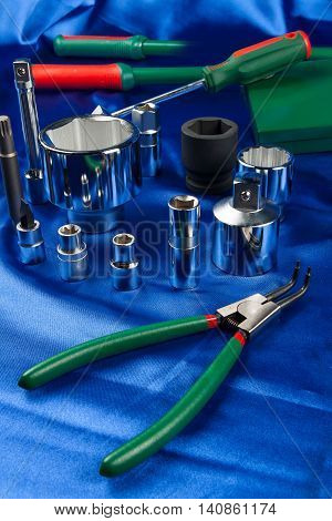 Mechanic tools set on blue silk background. The different sizes wrench socket and hand tools with green handles
