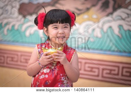 China Girl In Traditional Chinese Dress Greeting, Holding A Gold Ingot Standing