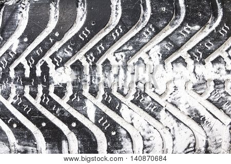 Old tire in grunge style. Black tread with white paint in the recesses