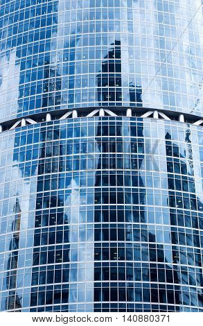 A background with the reflections of sky, clouds and buildings in the windows of a skyscraper.