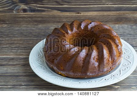 Bundt cake on a white plate  on a wooden background.