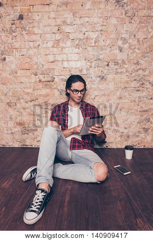 Young Man Sitting On Floor And Using Digital Tablet