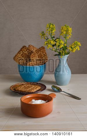 Breakfast with cheese and biscuits yellow flowers in a blue vase on a light background