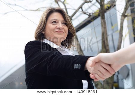 Close up of business woman hand shaking for making a deal. Outdoors.