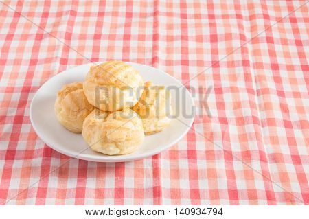 Eclair cream dessert in a dish on red and white chintz background.